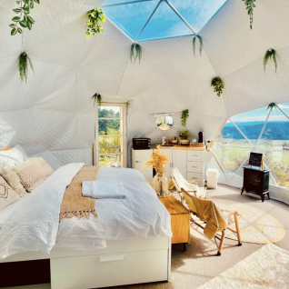 Interior of a luxurious glamping dome at Glamping Hohe Wand with cozy décor and panoramic window views.