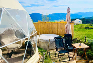 Glamping Hohe Wand - De dome mit Sitzbereich im Freien, Whirlpool und Blick auf grüne Berge und Täler.