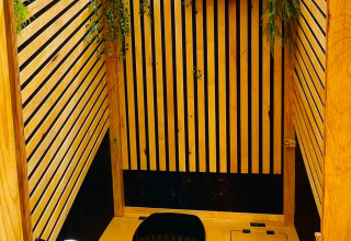 Modern eco-friendly bathroom with wooden slats and greenery at Glamping Hohe Wand - De dome, Netherlands.