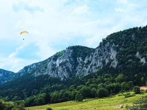 Glamping Hohe Wand - De dome: Skøn domecampingplads ved grønne bakker og træklædte bjerge, paraglider i luften.