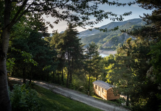 Glamping accommodatie bij Camping Huttopia Lac de Serre-Ponçon, omgeven door bos met uitzicht op het meer.