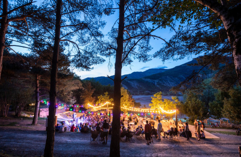 Glamping Camping Huttopia Lac de Serre-Ponçon dans les Alpes-de-Haute-Provence, soirée lumineuse, ambiance festive.