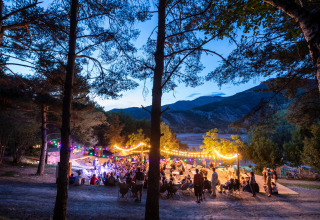 Zona de glamping Camping Huttopia Lac de Serre-Ponçon en Alpes-de-Haute-Provence con ambiente nocturno festivo.