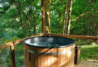 Bain à remous extérieur rond sur terrasse en bois, vue forêt, chez Nutchel - Lodges dans les Ardennes, Belgique.