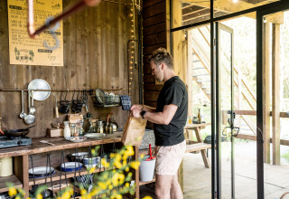 Homme cuisinant dans une cuisine de glamping confortable aux Nutchel Lodges dans les Ardennes, Belgique.
