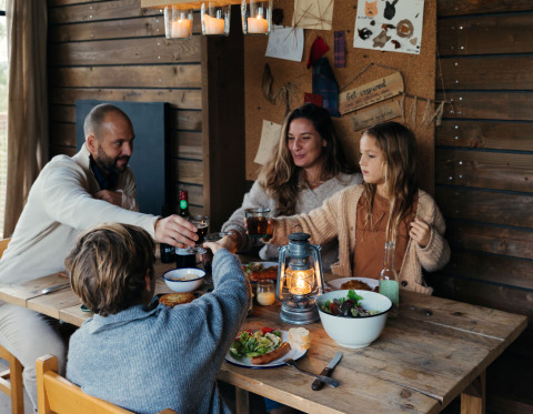 Gezin dineert gezellig in houten lodge bij Nutchel glamping in de Ardennen, België.