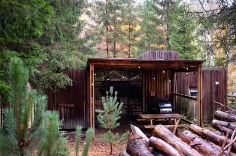 Alojamiento glamping en Nutchel - Lodges en las Ardenas, Bélgica, rodeado de bosque y terraza de madera.