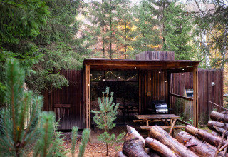 Alojamiento glamping en Nutchel - Lodges en las Ardenas, Bélgica, rodeado de bosque y terraza de madera.