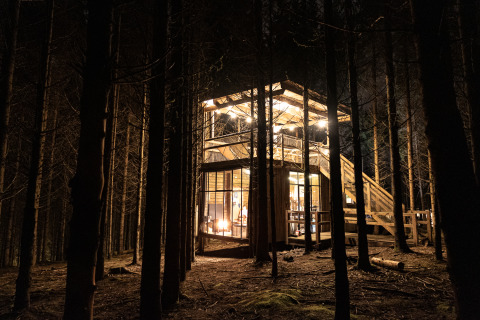 Lodge Nutchel illuminato nella foresta delle Ardenne, Belgio, di notte. Perfetto per il glamping unico.