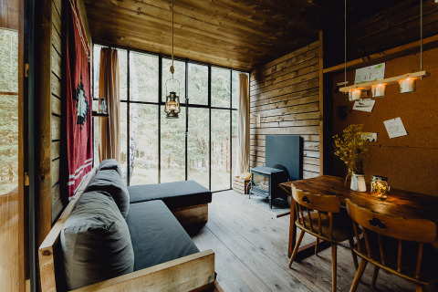 Innenansicht der Nutchel Glamping-Lodge in den Ardennen, Belgien, mit Holzwänden und großen Fenstern zur Natur.