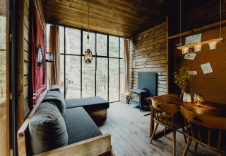 Vista interna del lodge glamping Nutchel nelle Ardenne, Belgio, con pareti in legno e grandi finestre sulla natura.