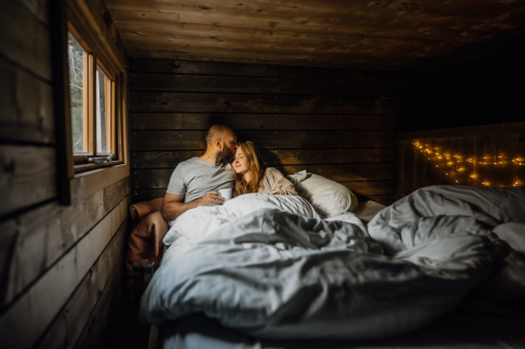 Couple détendu dans un lodge glamping Nutchel en bois, lumières féeriques, dans les Ardennes, Belgique.