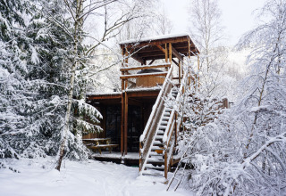 Winter glamping at Nutchel lodges in the Ardennes, Belgium, surrounded by snow-covered trees and forest.