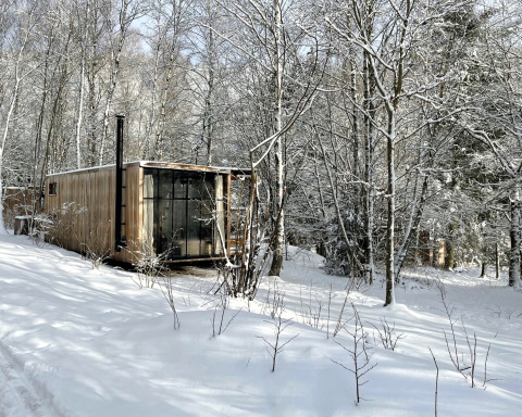 Alojamiento tipo lodge Nutchel en las Ardenas, Bélgica, rodeado de árboles nevados en invierno.