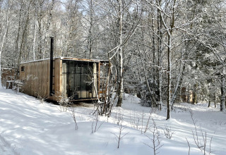 Nutchel-Lodge in den Ardennen, Belgien, umgeben von verschneiten Bäumen und winterlicher Landschaft.