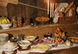 Rustikt morgenmadsbord med brød, frugt, ost, æg og syltetøj på Domaine Bonneblond Glamping i Auvergne.