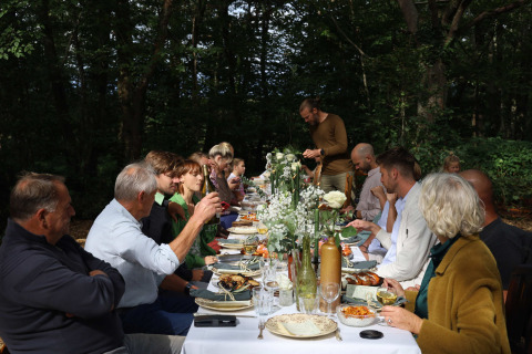 Gäste sitzen bei einem langen Tischdinner in der Natur im Domaine Bonneblond - Glamping Lodges Auvergne-Rhône-Alpes.