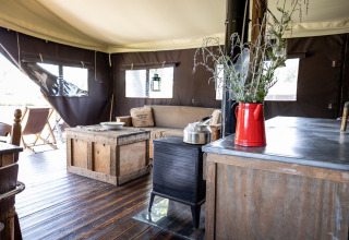 Intérieur d'un lodge glamping au Domaine Bonneblond, Auvergne-Rhône-Alpes, avec mobilier rustique en bois.