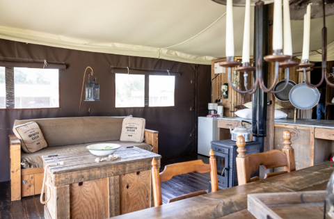 Indvendig udsigt af glamping lodge på Domaine Bonneblond med træmøbler, komfur og hyggelig stemning.