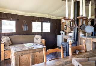 Innenansicht einer Glamping-Lodge im Domaine Bonneblond mit gemütlicher Einrichtung, Holzofen und rustikalen Möbeln.