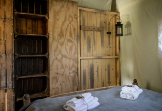 Intérieur d'une tente au Domaine Bonneblond Glamping Lodges Auvergne-Rhône-Alpes, bois rustique et serviettes.