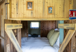 Gemütliche Glamping-Unterkunft Domaine Bonneblond mit Holzwänden und Bett in Auvergne-Rhône-Alpes.