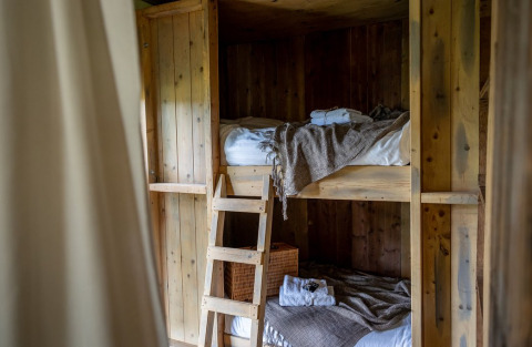 Letti a castello in legno rustici presso Domaine Bonneblond Glamping Lodges in Auvergne-Rhône-Alpes, atmosfera accogliente.