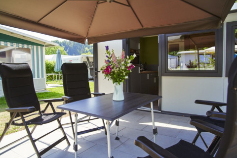 Udendørs spiseområde med fire sorte stole, et bord med blomster og en parasol på Campingplatz Kirchzarten.