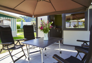 Terrasopstelling met vier zwarte stoelen en een tafel met bloemen bij Campingplatz Kirchzarten in het Zwarte Woud.