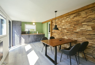 Hébergement glamping moderne avec mur en bois, table à manger et cuisine au Campingplatz Kirchzarten, Forêt-Noire.