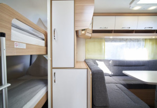 Interno dell’alloggio glamping al Campingplatz Kirchzarten con letti a castello e salotto nella Foresta Nera.