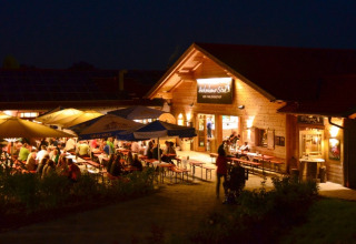 Avondeten buiten bij VITAL Camping Bayerbach - Lodges in Beieren, gezelligheid onder parasols met verlichting.