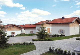 Vital Camping Bayerbach - Lodges en Baviera con techos rojos, áreas verdes y cielo azul con nubes blancas.