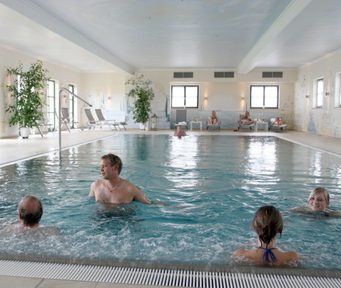 Indendørs pool på VITAL Camping Bayerbach - Lodges i Bayern med gæster, der slapper af og svømmer.