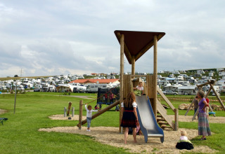 Kinderen spelen op een speeltuin bij VITAL Camping Bayerbach - Lodges, met veel caravans in Beieren.