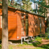 Wooden cabin in a forest with outdoor table and chairs at Vakantiepark Havelberge - Stacaravan Orlando glamping.