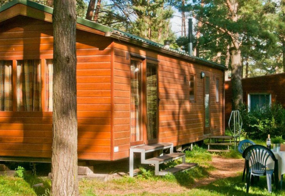 Casa mobile in legno nella foresta con tavolo e sedie all’aperto al Vakantiepark Havelberge - Stacaravan Orlando glamping.