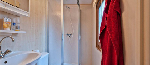 Moderne badkamer met douche, wastafel, toilet en rode badjas in de glamping van Vakantiepark Havelberge.