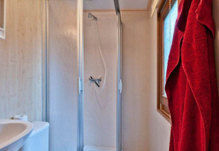 Modernes Badezimmer mit Dusche, Waschbecken, Toilette und rotem Bademantel im Vakantiepark Havelberge.