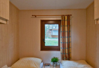 Twee enkele bedden in een lichte houten kamer met raam in Vakantiepark Havelberge - Stacaravan Orlando.