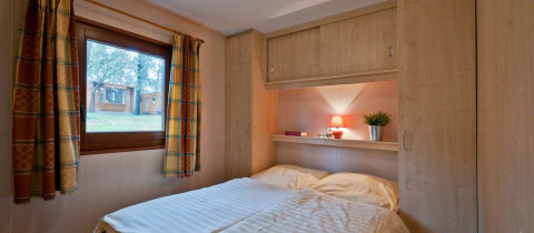 Interieur van een slaapkamer in Vakantiepark Havelberge - Stacaravan Orlando met een bed en raam op de natuur.