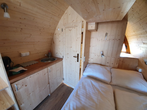 Interno di un accogliente pod glamping in legno con angolo cottura e letto nella Lüneburger Heide.