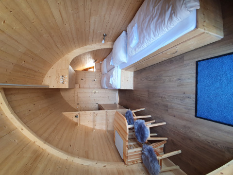 Vue intérieure d'un pod de camping moderne en bois avec lits et coin repas au Campingplatz Auf dem Simpel.