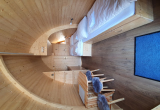 Innenraum eines modernen Campingpods aus Holz mit Betten und Essbereich auf Campingplatz Auf dem Simpel.