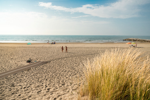 Beach view at Camping Ca Savio - Nordisk Village tents Venice, with people and tents scattered in the distance.