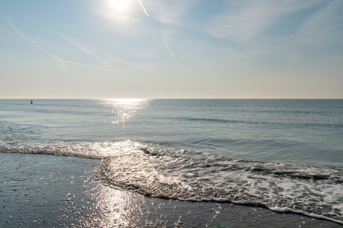 Vista sulla costa al Camping Ca Savio - Nordisk Village tende Venezia con il sole che illumina il mare calmo.