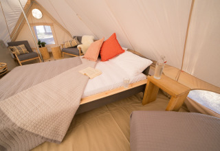 Luksuriøs glamping-indkvartering i Camping Ca Savio Nordisk Village telt med komfortable senge og hyggeligt interiør.