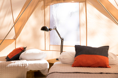 Interior of a glamping tent at Camping Ca Savio - Nordisk Village Venice with twin beds and a lamp.