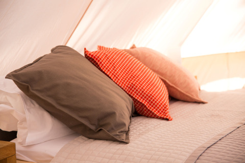 Zachte kussens op een bed in een glampingtent bij Camping Ca Savio - Nordisk Village vlakbij Venetië.
