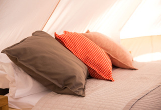 Gemütliches Bett mit Kissen im Glamping-Zelt von Camping Ca Savio - Nordisk Village bei Venedig.
